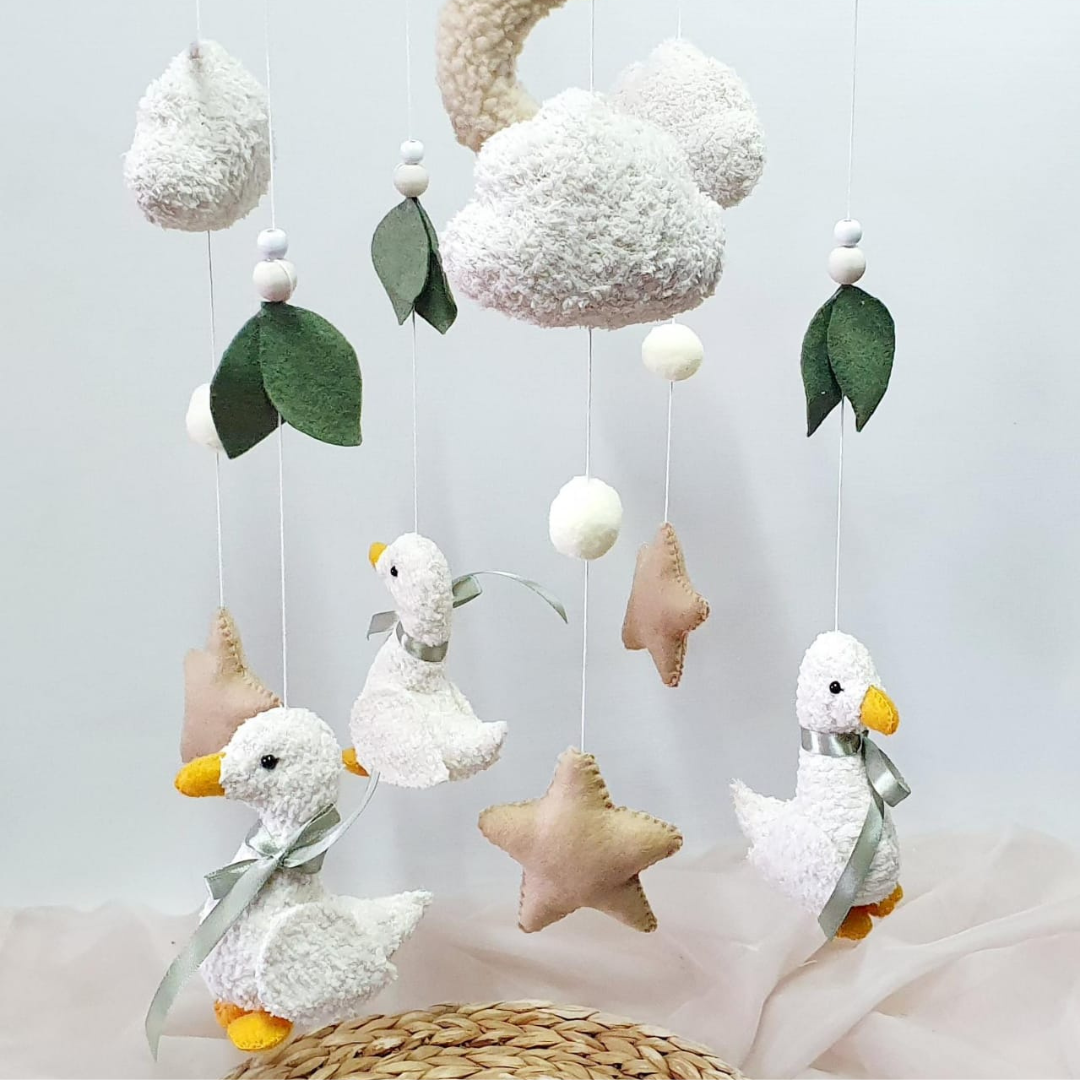 Baby mobile with ducks, stars, and clouds on a light background