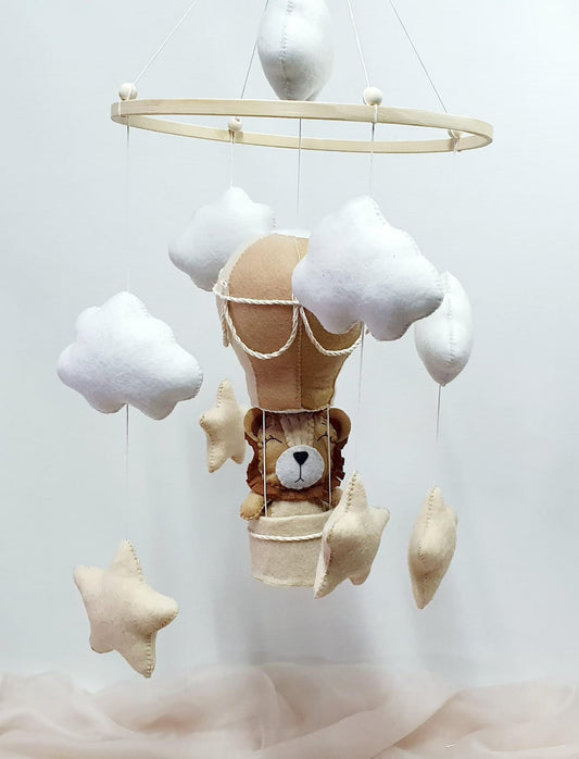 Children's mobile with teddy bear in a hot air balloon, clouds, and stars on a white background