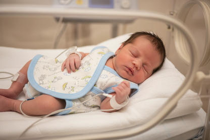 Newborn baby in an incubator wearng the NICU vest
