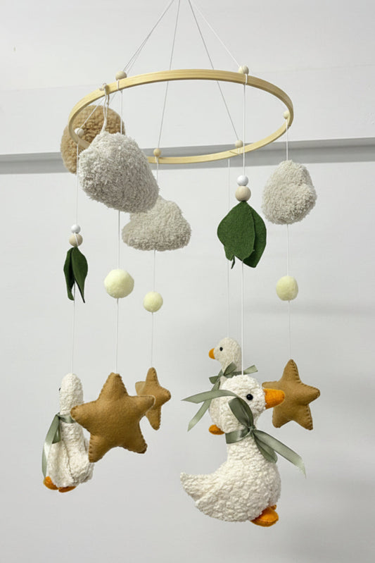 Decorative baby mobile with ducks, stars, and leaves on a plain background