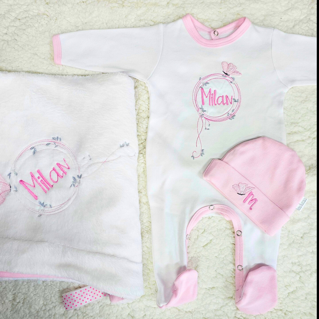 Baby outfit set with onesie, hat, and blanket featuring the name '米兰' on a textured surface.