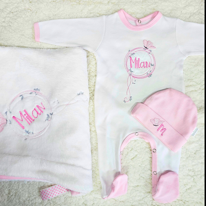 Baby outfit set with onesie, hat, and blanket featuring the name '米兰' on a textured surface.
